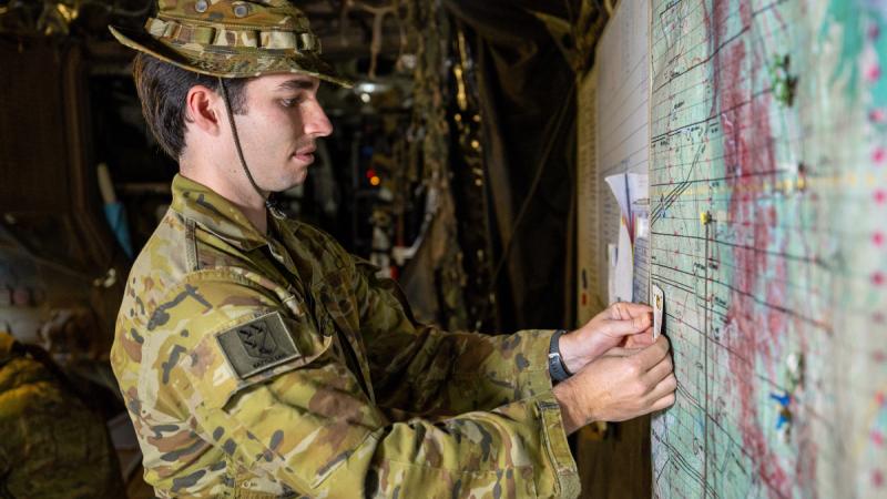 Soldier pins playing card to map on the wall.