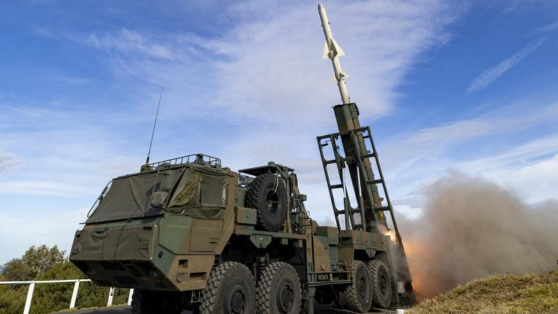 A white surface-to-ship missile is launched from a six wheel military vehicle against the back drop of a blue sky.