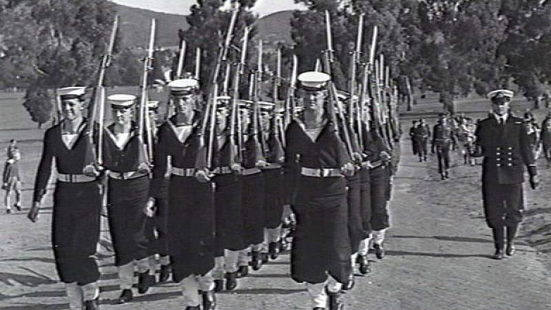 Naval personnel from Harman march in formation along a Canberra track.