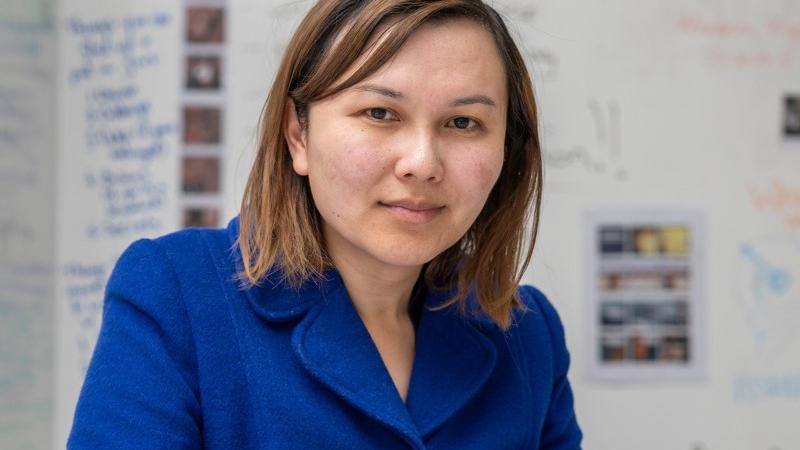 A woman in a blue coat works on a creative writing project.