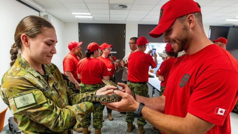 Australian Army soldier Private Kaitlyn Gallagher, left, from 1st Health Battalion, hands over a juvenile saltwater crocodile to a soldier from 4th Canadian Ranger Patrol Group during the Exercise Southern Cross 2025 fauna workshop in Darwin.