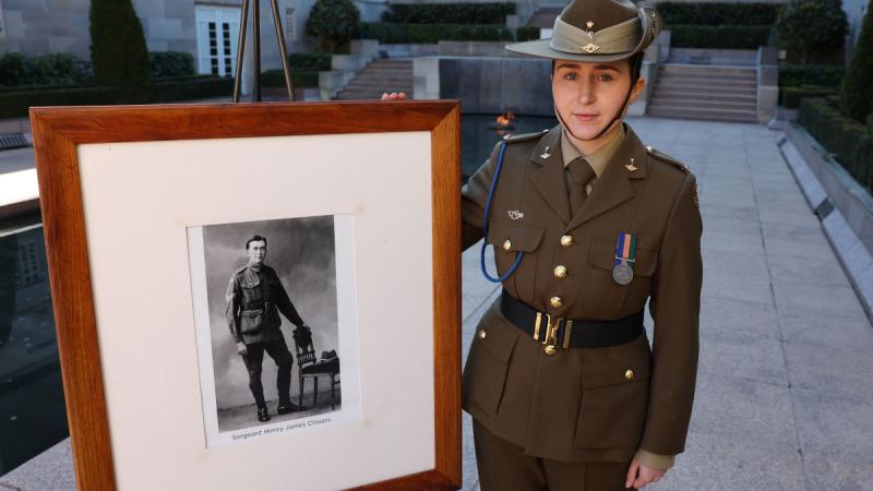 An Australian Army soldier holds a portrait of a relative at the Australian War Memorial.