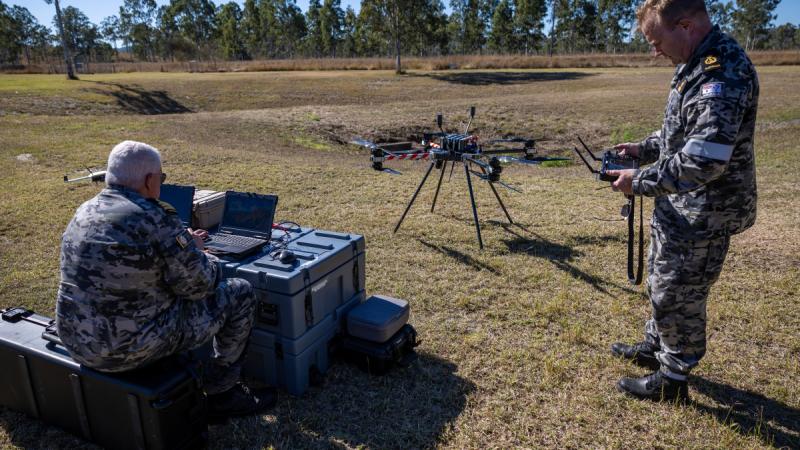 Two men outdoors setting up the Callisto 50 drone using a computer and hand-held controls.