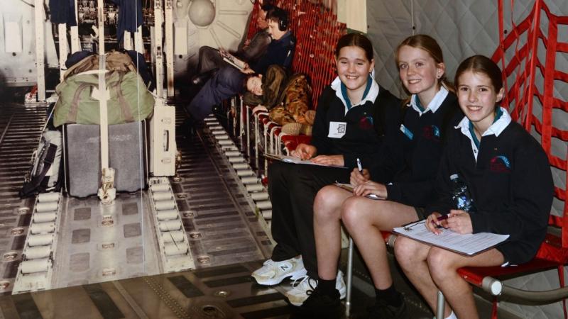 Students try the seating in a C-130 Hercules aircraft display.