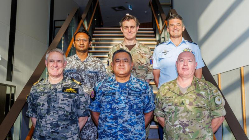 A group photo of the 5 chiefs of joint operations and Air Vice Marshal Christie standing on the stairs.
