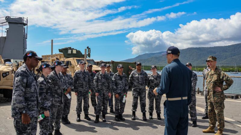 A group of recruits standing on the quay listening to a member of the US Navy speak.