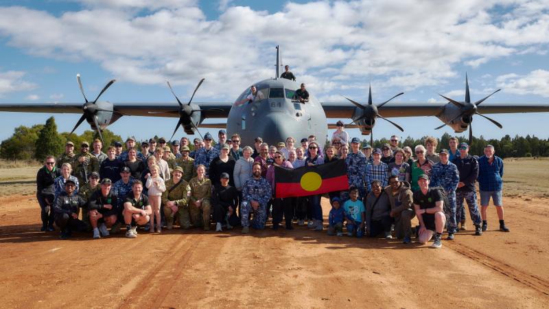ADF members, NRL representatives and Gilgandra locals gather in front of a Hercules aircraft.