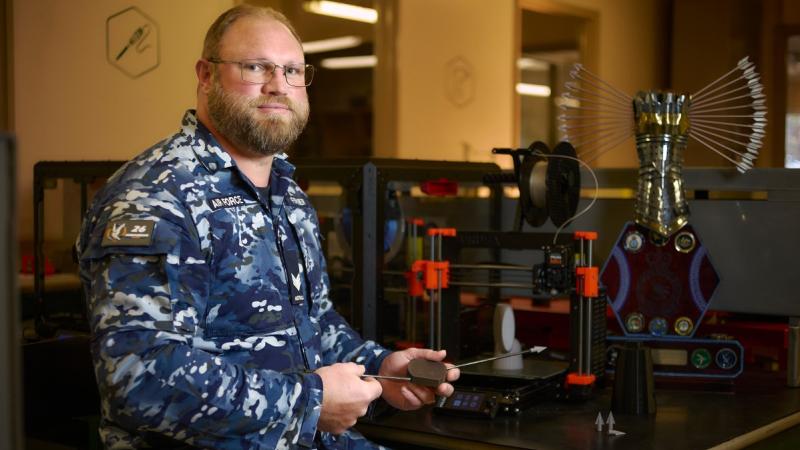 Air Force member in blue camouflage uniform works on a trophy in the Edgy Lab at RAAF Base Williamtown.
