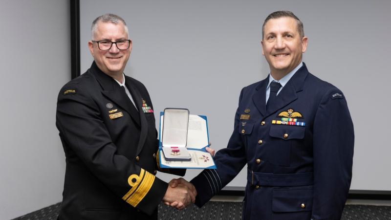 Senior naval officer presents US Legion of Merit to an Air Force officer. 