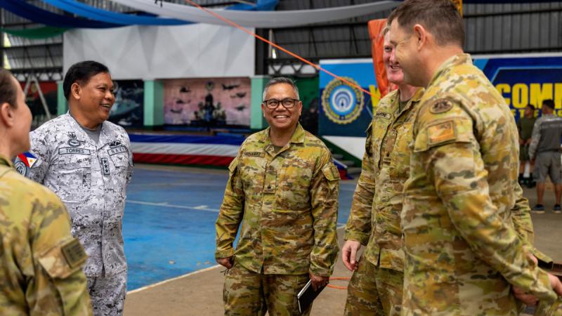 An Australian Army officer speaks to senior Filipino and Australian officers beside a swimming pool in the Philippines.