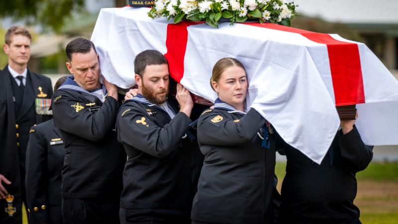 Navy sailors carry the coffin of a World War 2 veteran draped in the Australian ensign.