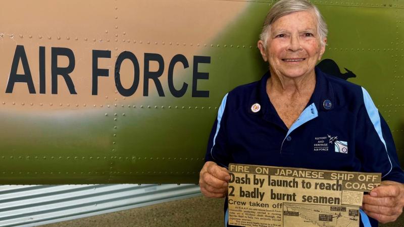 RAAF veteran holds a historic newspaper front page at RAAF Townsville Aviation Heritage Centre