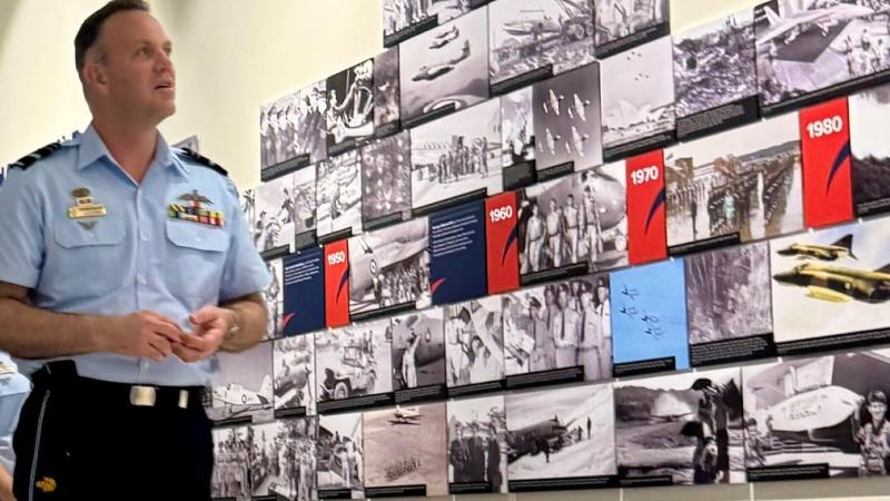 Air Force officer views historic photographs at the reopening of the RAAF Townsville Aviation Heritage Centre.