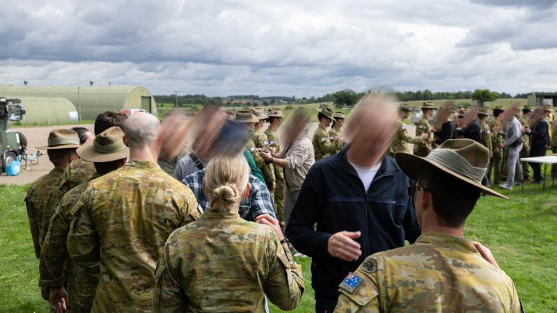 Soldiers line up to shake hands under a cloudy northern sky.