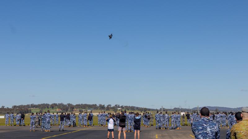 A crowd of people watching a plane during an aerial display.