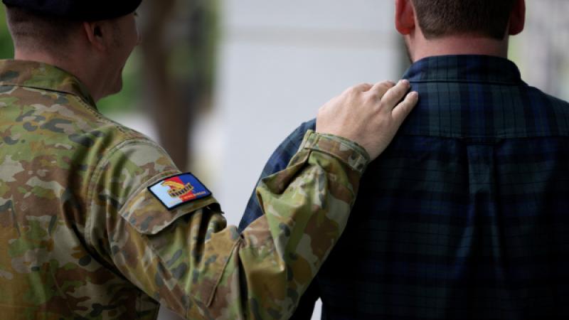 A soldier rests his hand on another man's shoulder in what looks like a gesture of support.