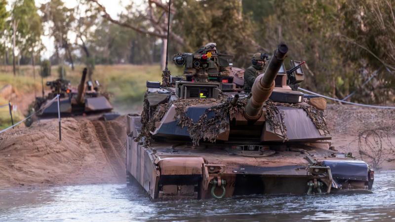 One tank driving into a river, another tank behind it.