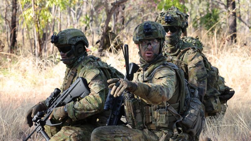 Australian soldiers in combat gear conduct an exercise in the bush.