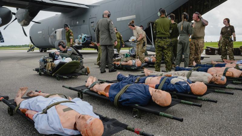 Military personnel lay out medical dummies outside an aircraft.