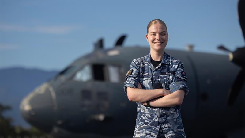 A smiling woman in Air Force uniform stands in front of an aircraft.