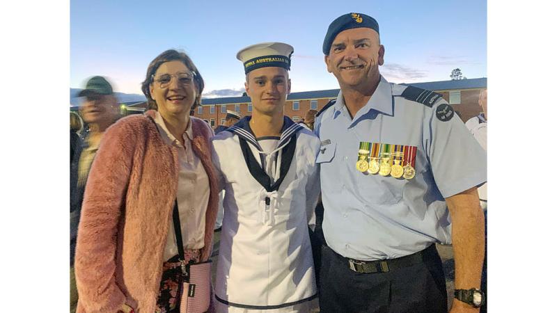 Two men in military uniform posing with a civilian woman for a photo.