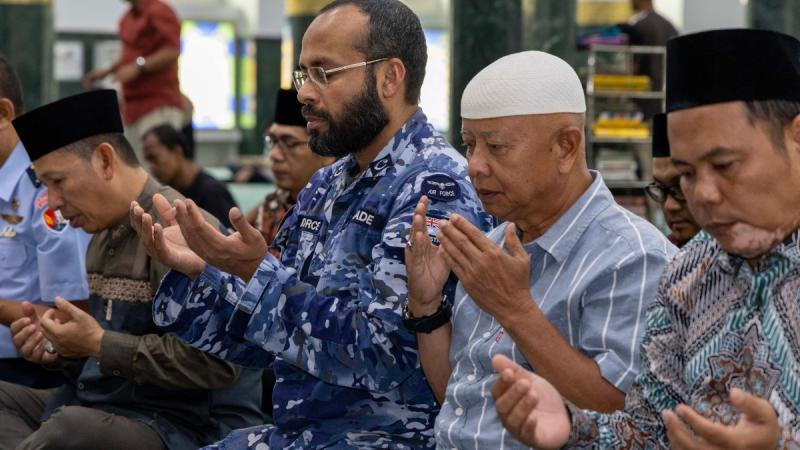 A man in Air Force uniform prays alongside others in Indonesia dress at a mosque.