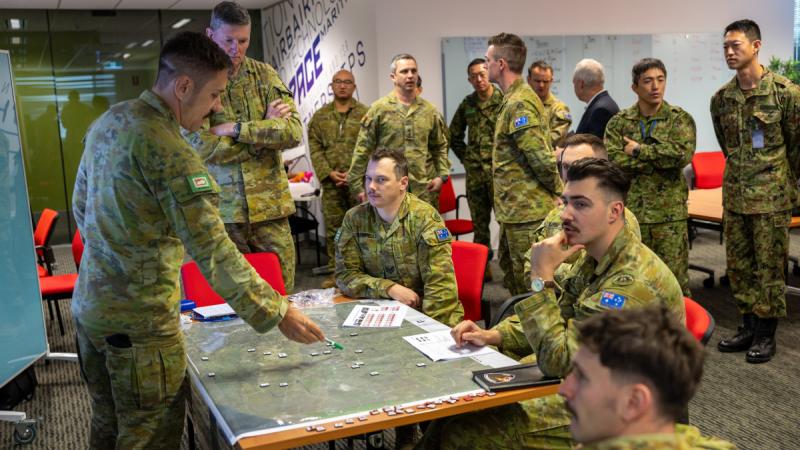 A group of soldiers standing around a tactical table as one points to something on a map.
