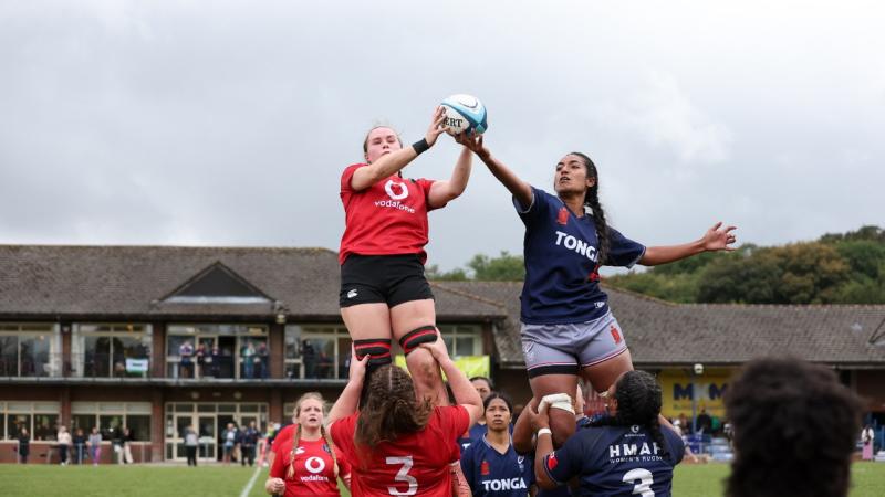 Two women being lifted by teammates in a lineout lift competing for a rugby ball.
