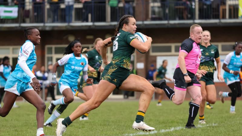 A woman running with the ball in a rugby game.