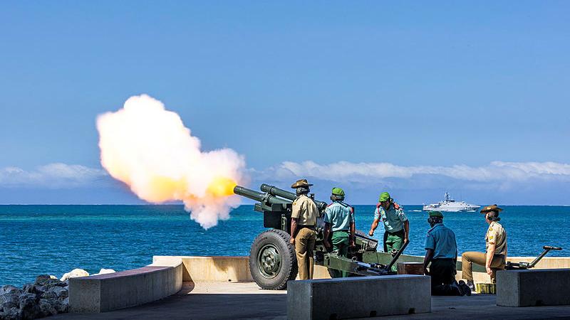 Australian and PNG soldiers fire a ceremonial gun salute at Port Moresby harbour.
