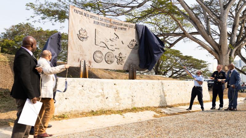 People unveiling a large sign.