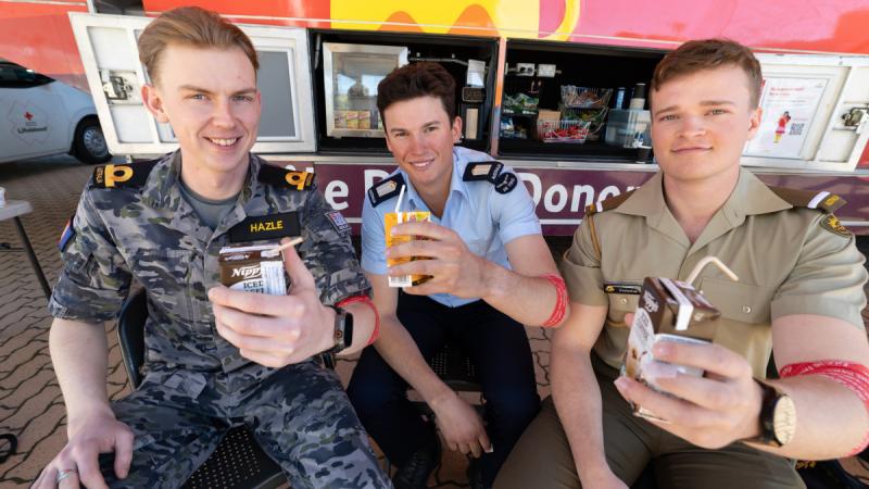 Three ADF cadets hold up juice boxes.