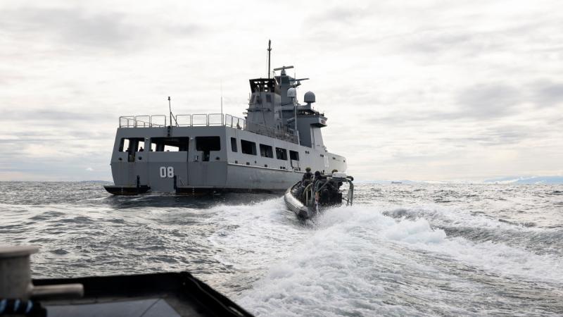 A small boat speeding towards a ship.