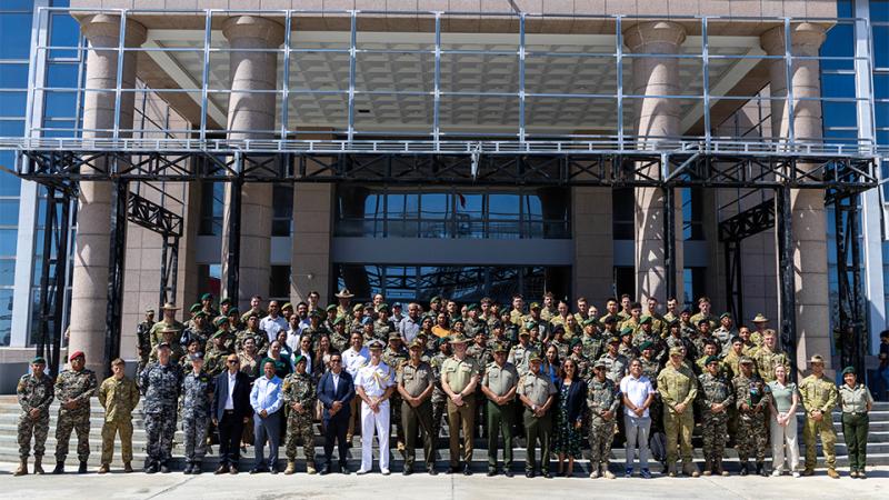 A large group photo, with people standing on stairs outside a large building.
