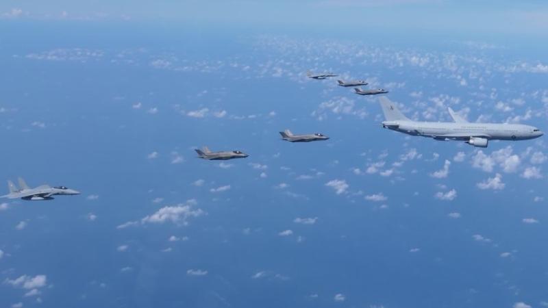 Fast jets from Australia, Japan and the US form up behind a tanker aircraft in flight.