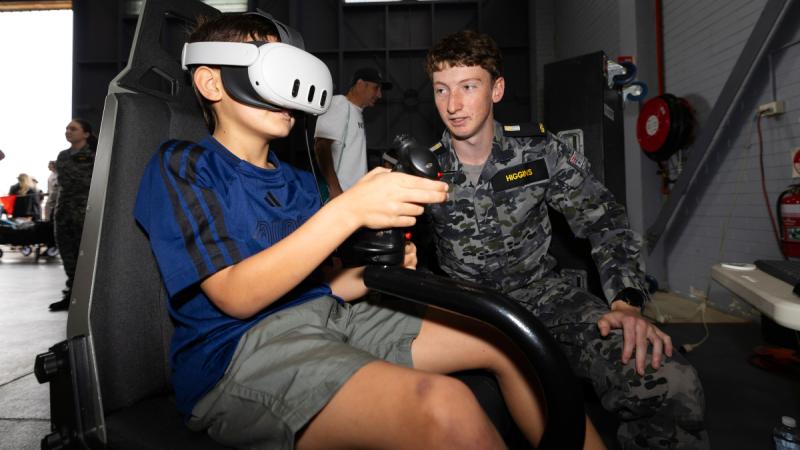 A Royal Australian Navy Midshipman Patrick Higgins guides a young member of the public through the MH-60R simulator during Richmond Air Show 25 at RAAF Base Richmond, NSW.