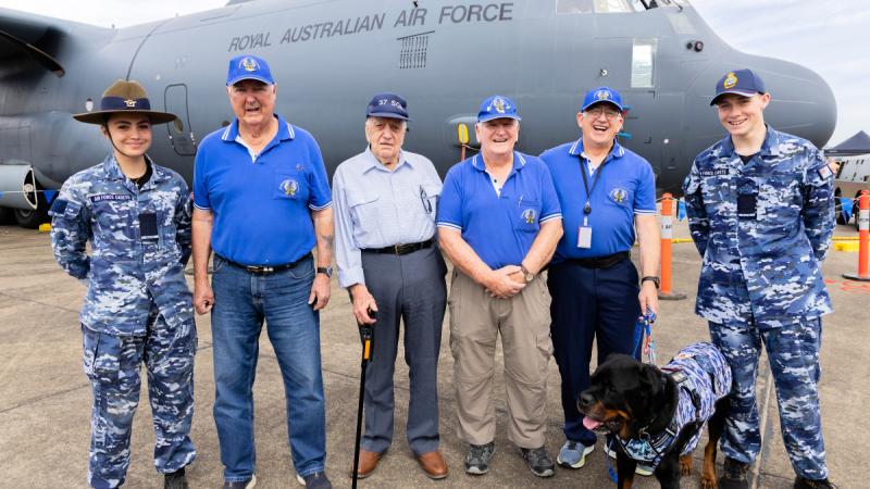 (L-R) Cadet Katelyn Wichman and Cadet Oscar Brown of the Royal Australian Air Force Cadets stand with former Royal Australian Air Force C-130 Hercules Loadmasters; Mr Bob Pearman, Mr Herman ‘Dave’ Jones, Mr Cole Coyne, Mr Stue Hablethwaite and his Service Dog at the 2025 RAAF Richmond Air Show, NSW.