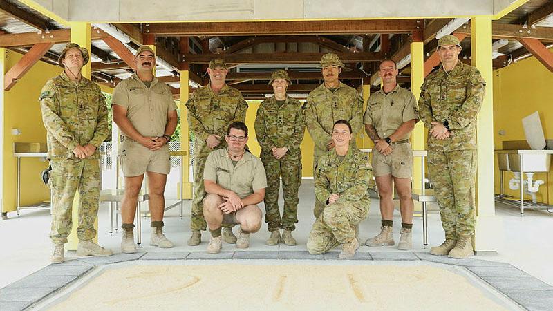Nine military personnel in uniform posing for a photo.