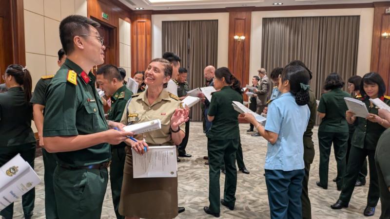 People in the military uniform of several countries mingling at a social gathering.