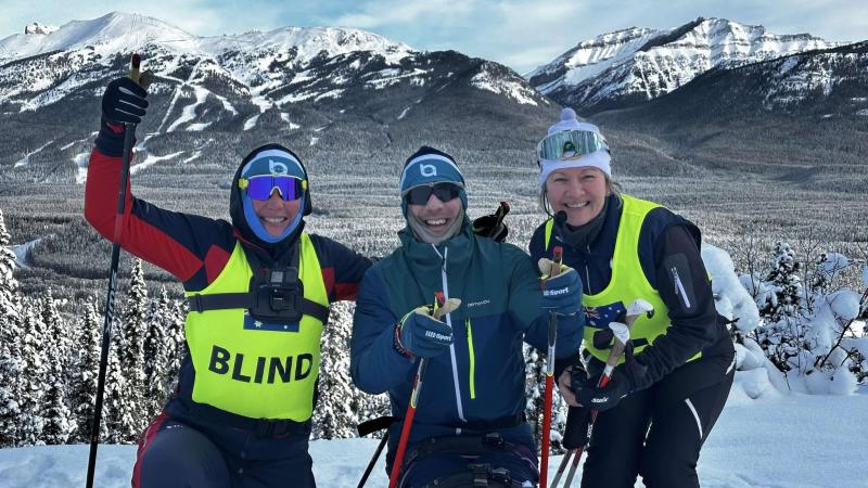 Three people stand in the snow during training for the Winter Paralympics.