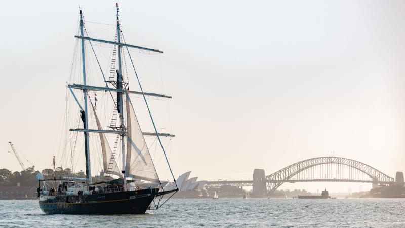A tall ship sailing in Sydney Harbour, with the Sydney Opera House and the Sydney Harbour Bridge in the background.