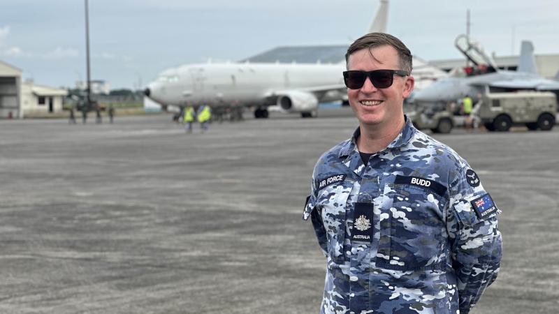A man in military uniform standing in front of an aircraft.