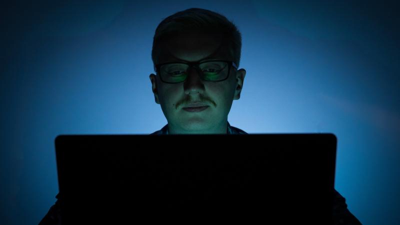 An Air Force officer operates a computer in semi-darkness.
