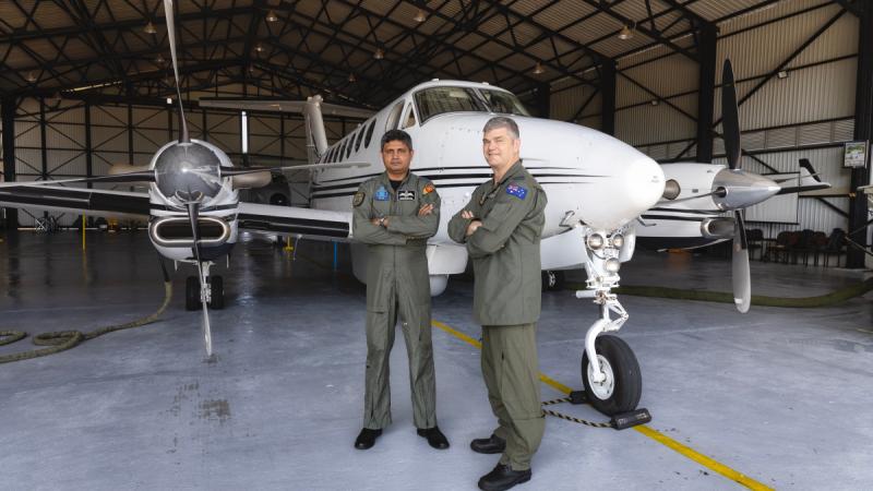A Sri Lankan and an Australian air force officer stand in front of a Beechcraft King Air 350 aircraft in a hangar.