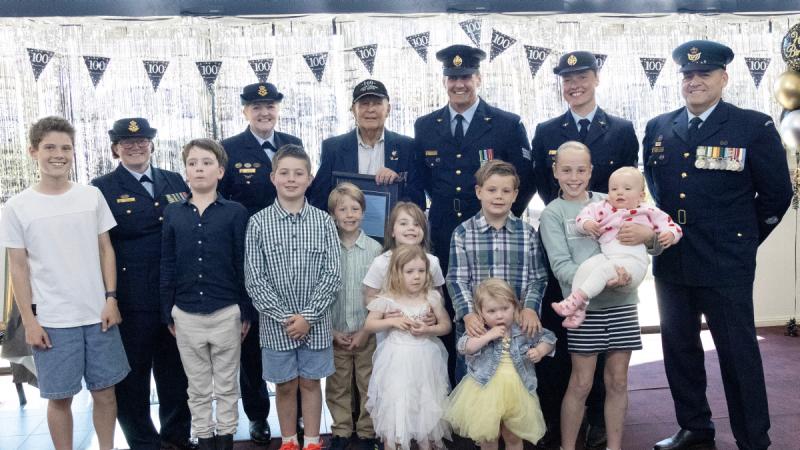A World War 2 veteran celebrates his 100th birthday with young relatives and Air Force members.