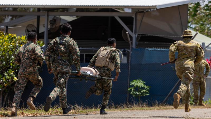 Soldiers running. Two are bearing a stretcher.