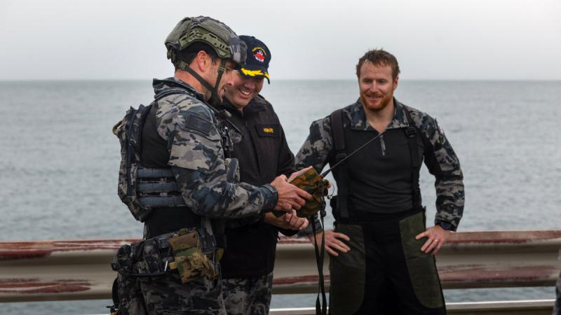 Navy personnel on a jetty discuss explosive ordnance disposal.