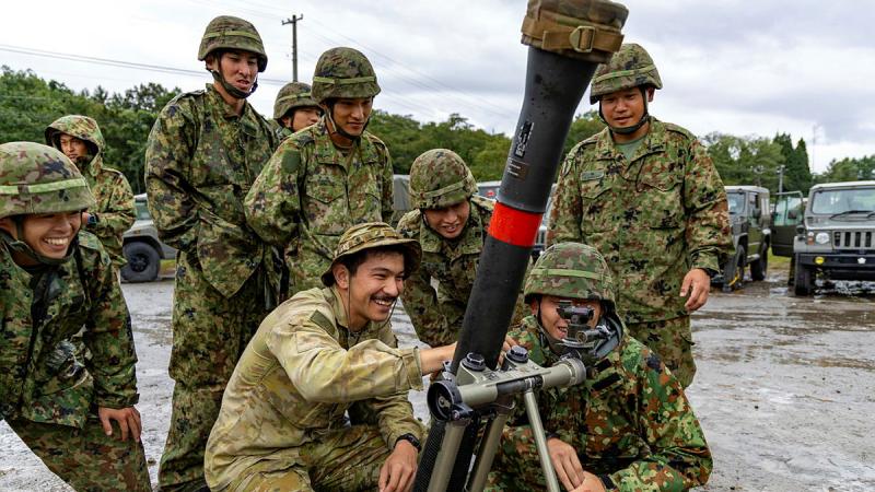 A group of soldiers crows around a mortar, pointed to the sky.