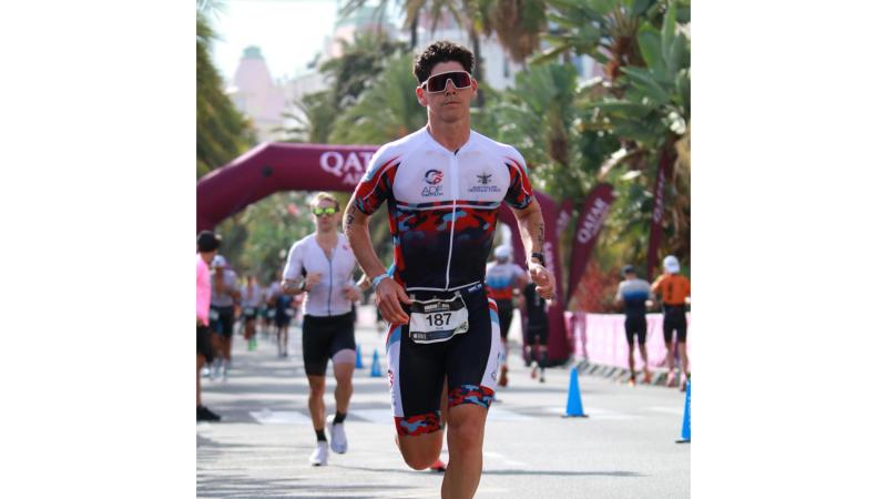 A man runs in front of others on a sunny day.