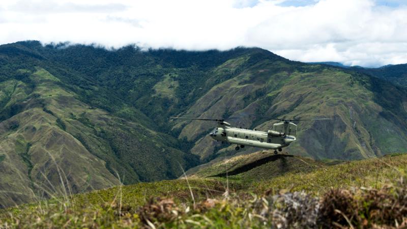 An Army Chinook flying low above green mountains in Papua New Guinea’s Central Highlands.
